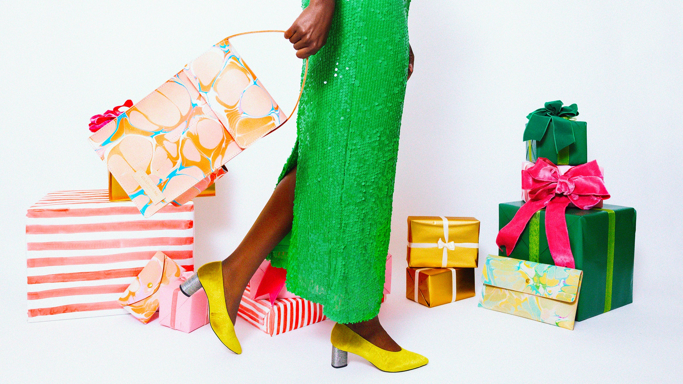 Woman walking in front of colorfully wrapped gifts, swinging a structured wine bag bag behind her as she walks